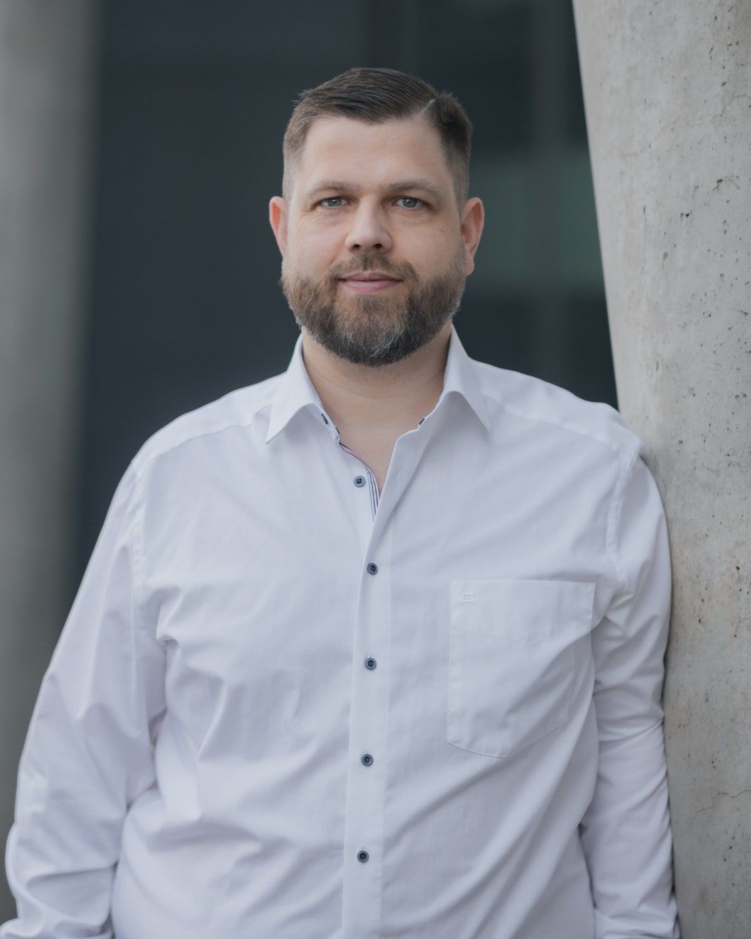 Benjamin Juling in weißem Hemd, an eine Betonsäule gelehnt
